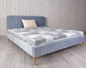 Duże niebieskie łóżko na drewnianych nóżkach