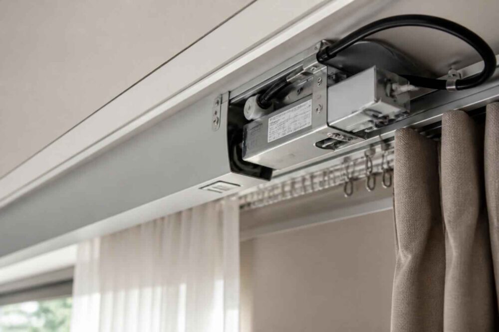 Mechanizm elektrycznego karnisza zamontowany przy suficie nad zasłonami.